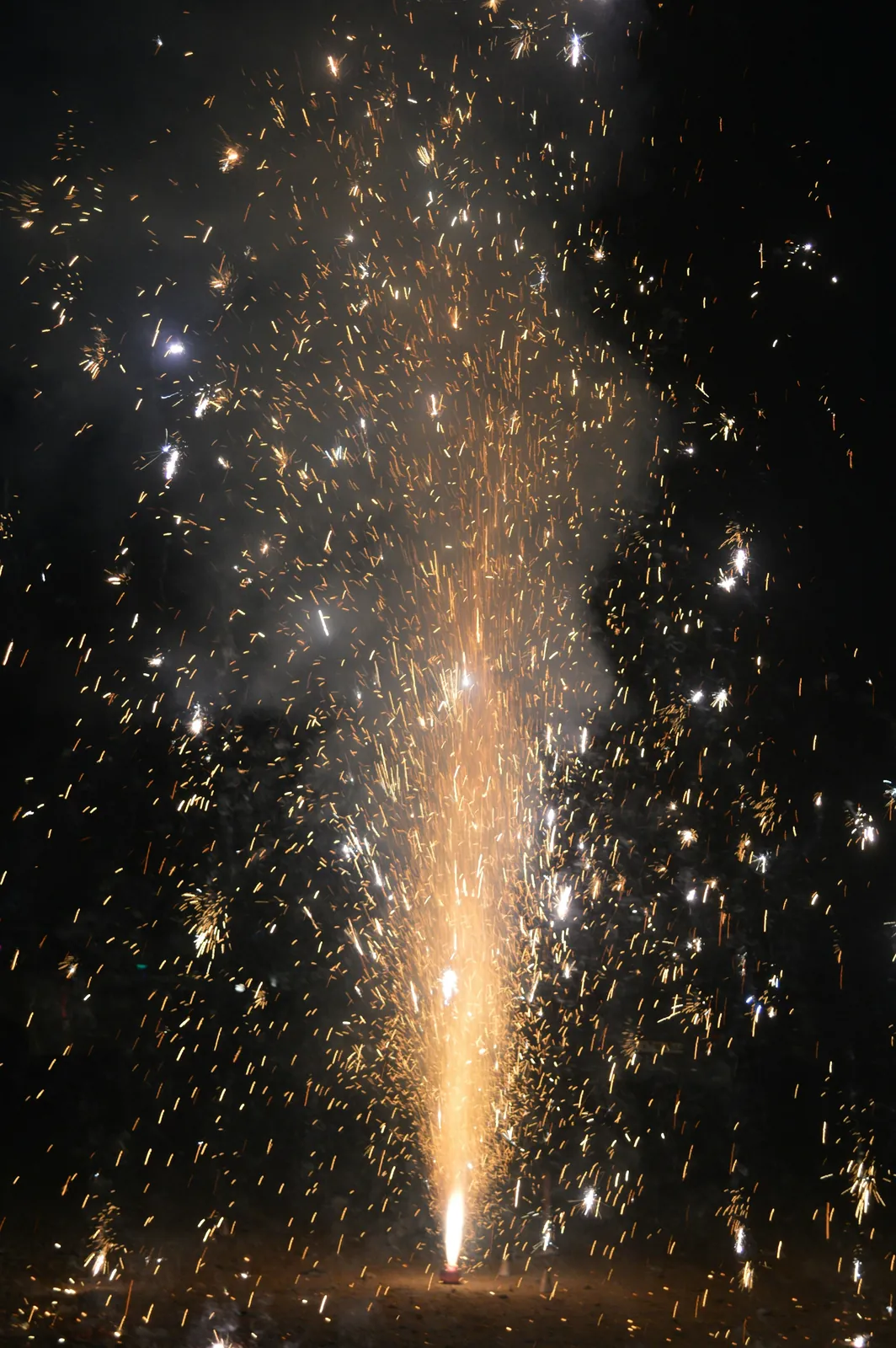 A flower-pot firework erupting in a fountain of golden sparks